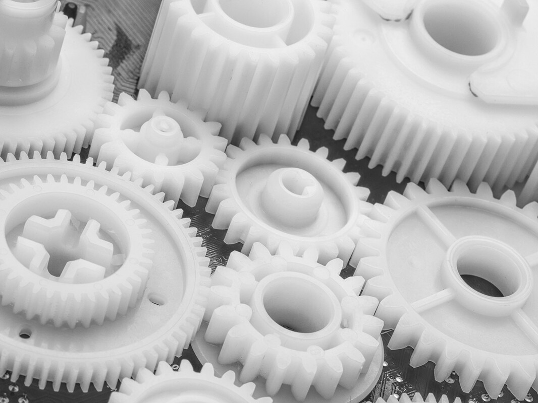 Close up of white plastic gears of different sizes.