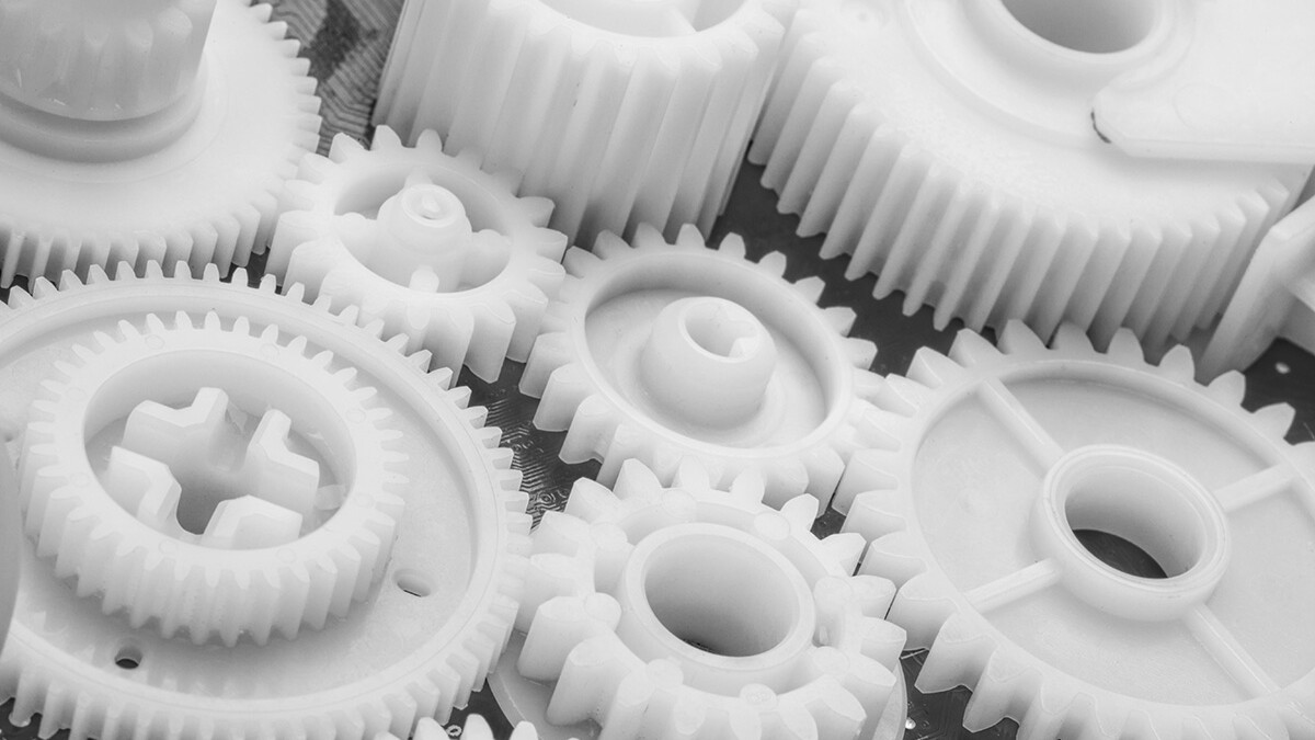 Close up of white plastic gears of different sizes.