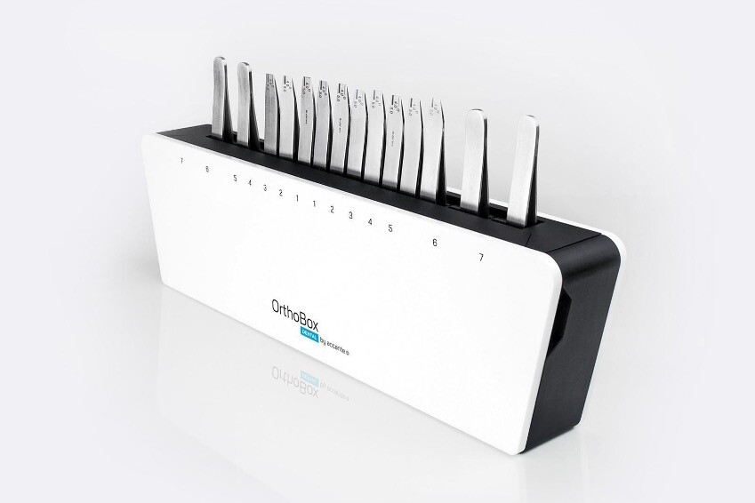 A white box from which the ends of orthodontic devices (metal tweezers) look out at the top.